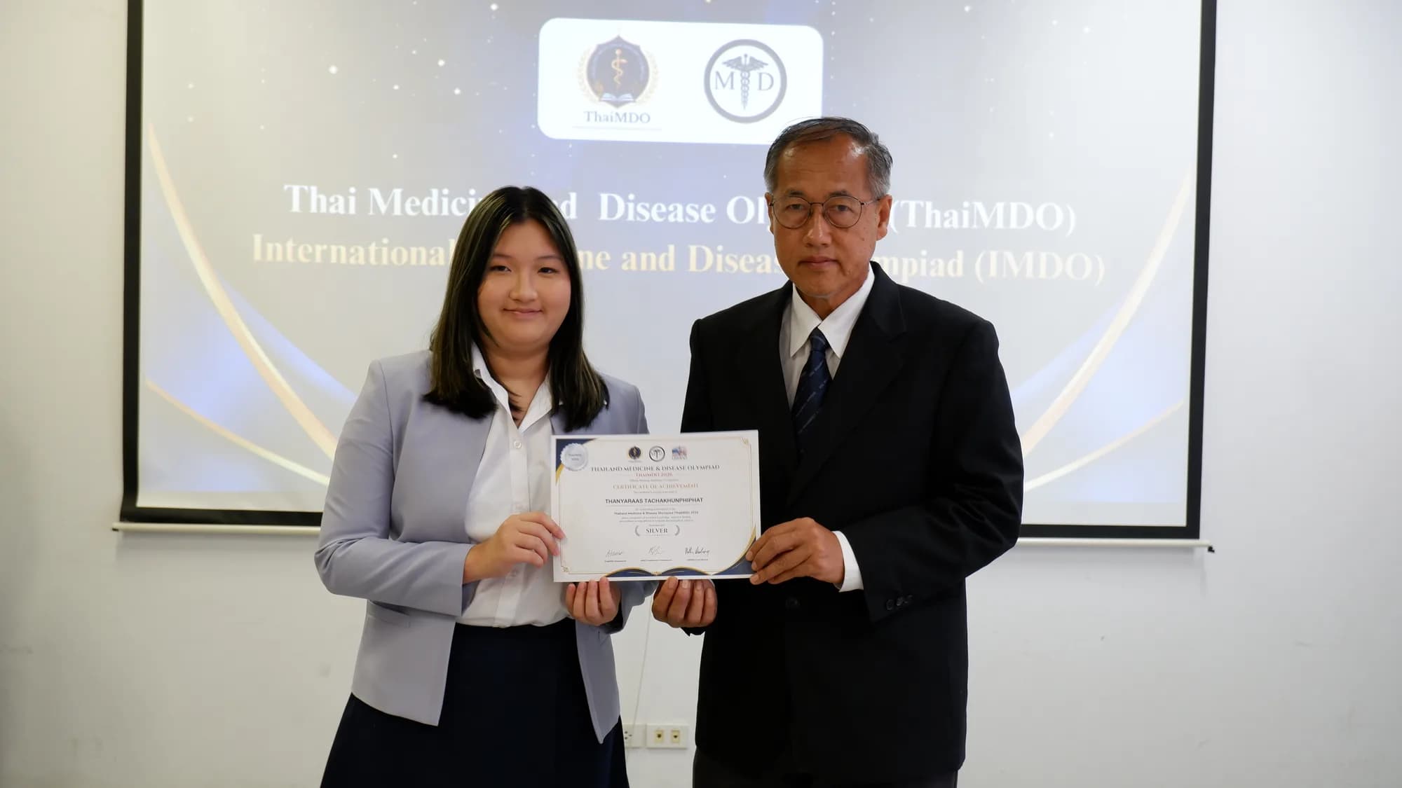 Another student receives a certificate from a committee member in the same ceremony setting.